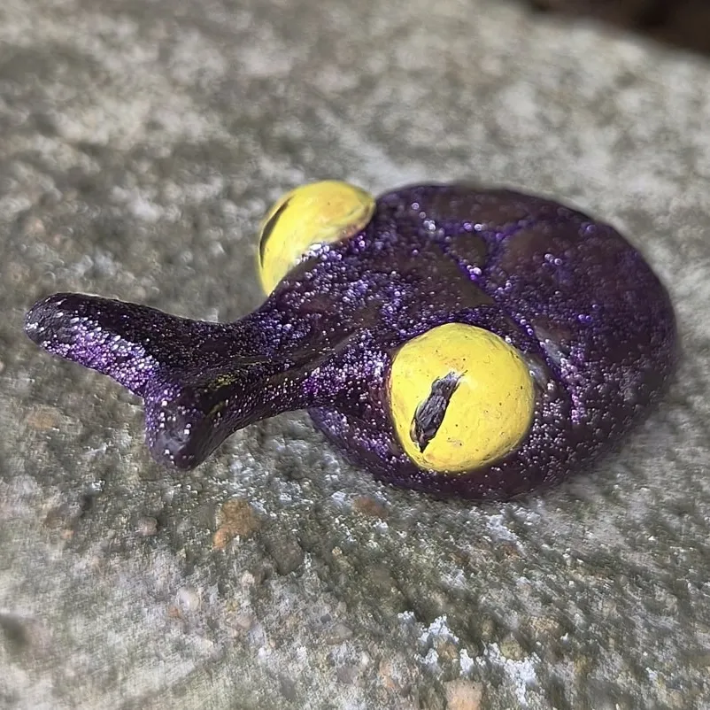 Glittery purple beetle with yellow eyes.